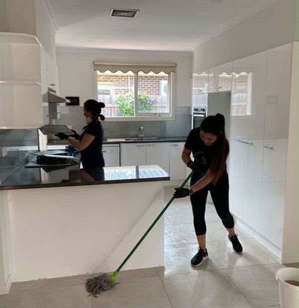 Two R U Helens team members cleaning a modern kitchen